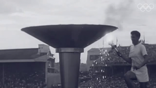 a black and white photo of a man lighting a torch