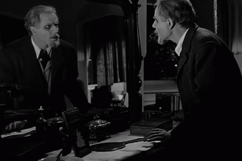 A Black And White Photo Of A Man Looking At Himself In The Mirror GIF