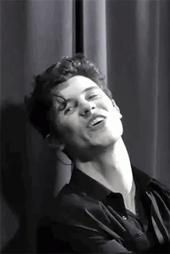 A Black And White Photo Of A Man Making A Funny Face While Standing In Front Of A Curtain . GIF