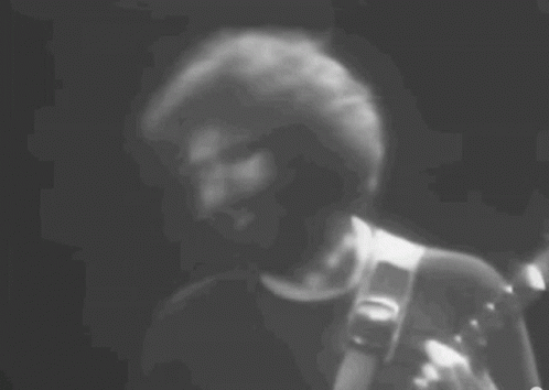 A Black And White Photo Of A Man Playing A Guitar . GIF