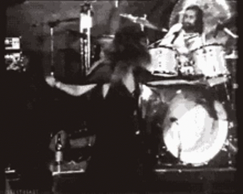 A Black And White Photo Of A Man Playing Drums In A Band GIF