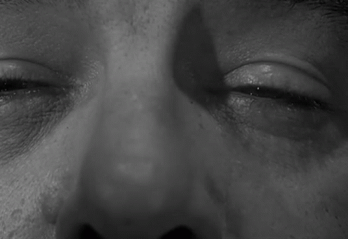 A Black And White Photo Of A Man 'S Eyes With A Shadow On His Face GIF