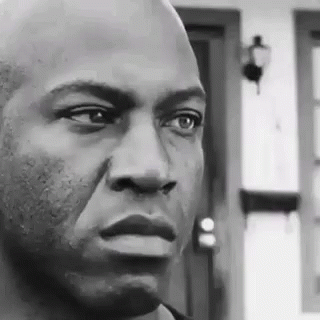 A Black And White Photo Of A Man 'S Face With A Door In The Background . GIF