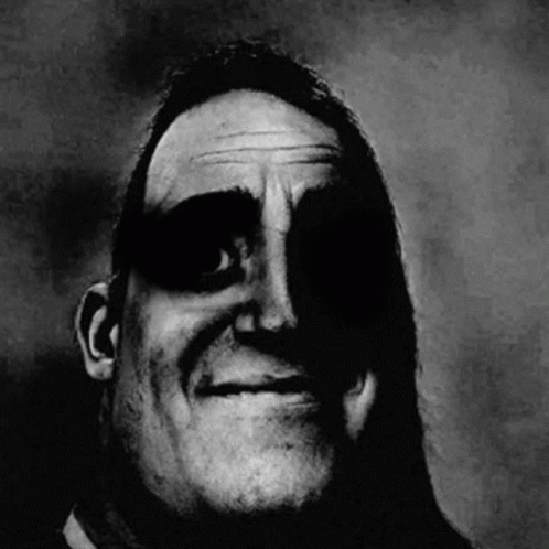 A Black And White Photo Of A Man 'S Face With A Shadow On It . GIF