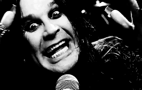A Black And White Photo Of A Man Singing Into A Microphone With His Mouth Open . GIF