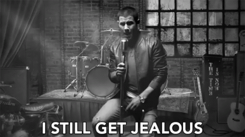 A Black And White Photo Of A Man Singing Into A Microphone With The Words I Still Get Jealous Below Him GIF