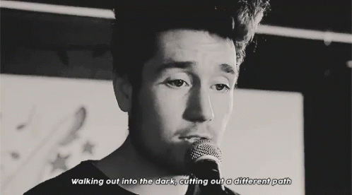 A Black And White Photo Of A Man Singing Into A Microphone With The Words Walking Out Into The Dark Cutting Out A Differ GIF