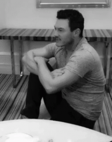 A Black And White Photo Of A Man Sitting On The Floor GIF