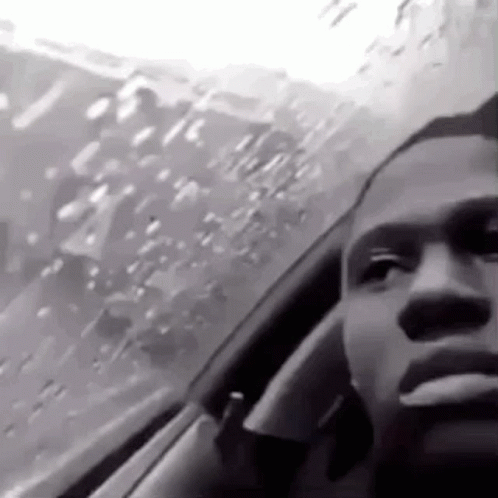 A Black And White Photo Of A Man Smoking A Cigarette While Sitting In A Car . GIF