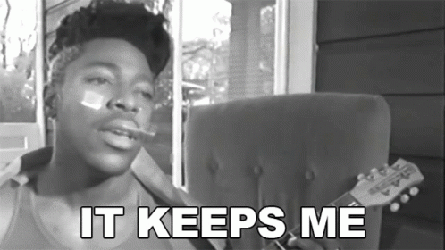 A Black And White Photo Of A Man Smoking A Cigarette With The Words " It Keeps Me " Below Him GIF