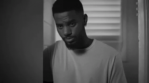 A Black And White Photo Of A Man Standing In A Doorway . GIF