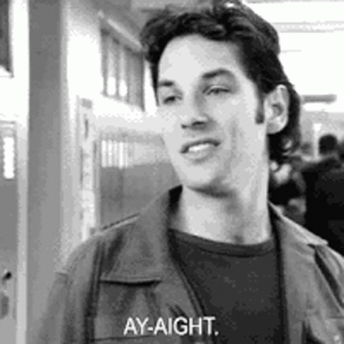 A Black And White Photo Of A Man Standing In A Hallway Talking To Someone . GIF
