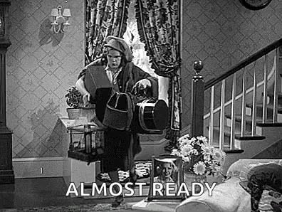 A Black And White Photo Of A Man Standing In A Living Room Holding A Bag . GIF