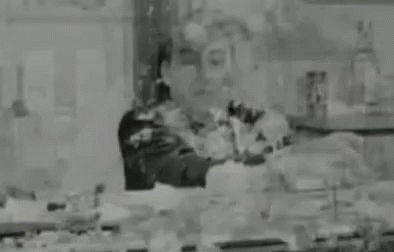 A Black And White Photo Of A Man Standing In A Room Covered In Paint . GIF