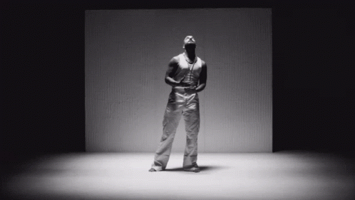 A Black And White Photo Of A Man Standing In Front Of A Cardboard Box GIF