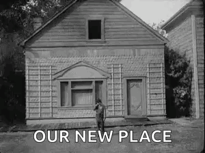 A Black And White Photo Of A Man Standing In Front Of A House With The Words `` Our New Place '' Above Him . GIF