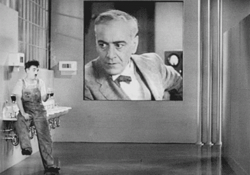 A Black And White Photo Of A Man Standing In Front Of A Large Screen GIF