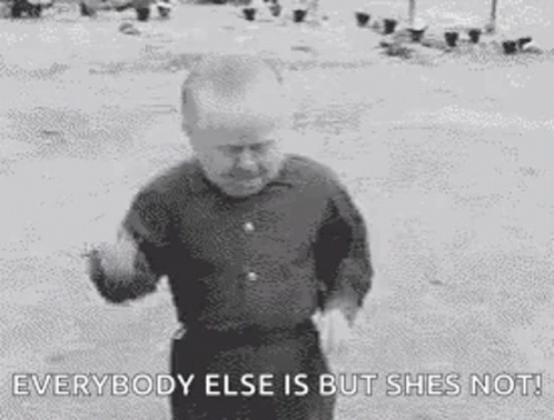 A Black And White Photo Of A Man Standing In The Dirt With The Words `` Everybody Else Is But She 'S Not '' . GIF