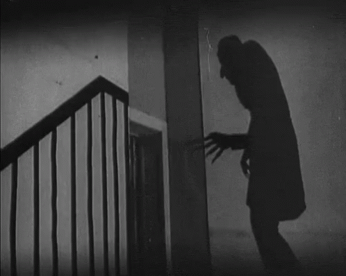 A Black And White Photo Of A Man Standing Next To A Staircase GIF