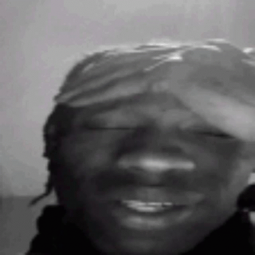 A Black And White Photo Of A Man Wearing A Bandana Smiling With His Eyes Closed . GIF