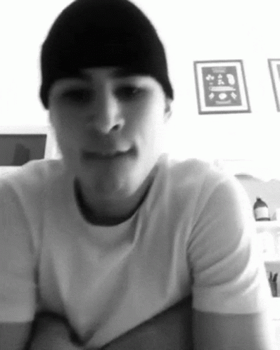 A Black And White Photo Of A Man Wearing A Beanie And A White T-Shirt GIF