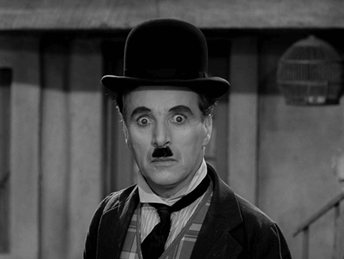 A Black And White Photo Of A Man Wearing A Bowler Hat GIF