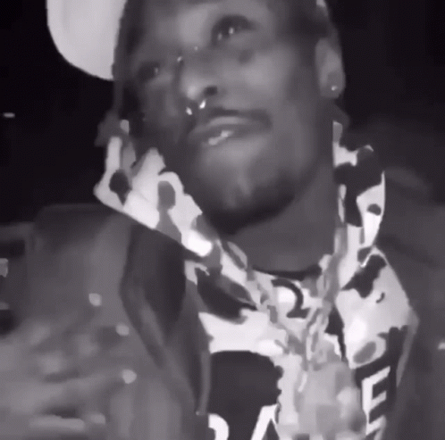 A Black And White Photo Of A Man Wearing A Camo Jacket GIF