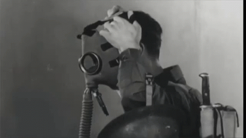 A Black And White Photo Of A Man Wearing A Gas Mask And A Knife GIF