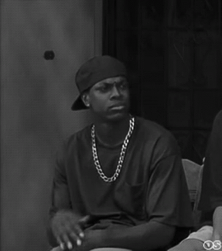 A Black And White Photo Of A Man Wearing A Hat And A Necklace . GIF