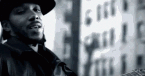 A Black And White Photo Of A Man Wearing A Hat And Holding A Guitar . GIF