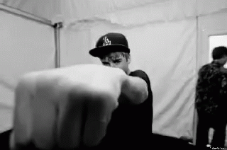 A Black And White Photo Of A Man Wearing A Hat Pointing His Finger At The Camera . GIF