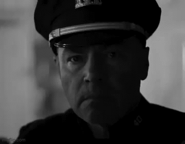 A Black And White Photo Of A Man Wearing A Police Hat . GIF