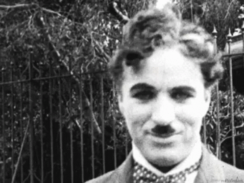 A Black And White Photo Of A Man Wearing A Suit And Bow Tie . GIF