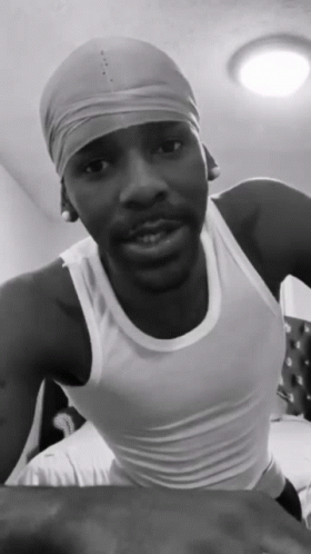 A Black And White Photo Of A Man Wearing A White Tank Top And A Headband GIF