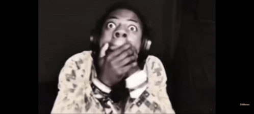 A Black And White Photo Of A Man Wearing Headphones And Covering His Mouth . GIF