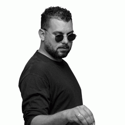 A Black And White Photo Of A Man Wearing Sunglasses And Waving His Hand GIF