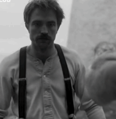 A Black And White Photo Of A Man Wearing Suspenders And A Shirt GIF