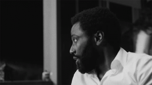 A Black And White Photo Of A Man With A Beard And A White Shirt GIF