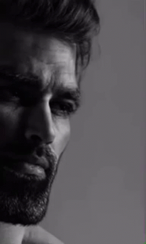 A Black And White Photo Of A Man With A Beard Looking At The Camera . GIF