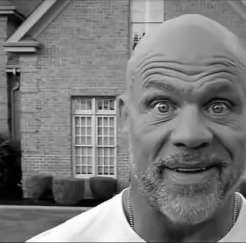 a black and white photo of a man with a beard making a funny face in front of a brick house .