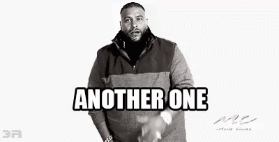A Black And White Photo Of A Man With A Beard Wearing A Sweater And Standing With His Hands In His Pockets . GIF