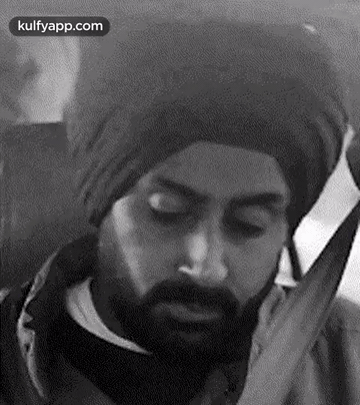 A Black And White Photo Of A Man With A Beard Wearing A Turban And Talking On A Cell Phone . GIF