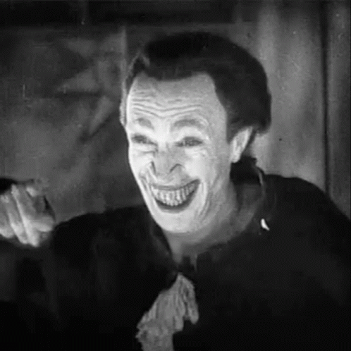 A Black And White Photo Of A Man With A Joker Mask On His Face . GIF
