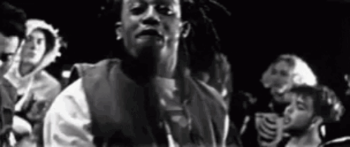 A Black And White Photo Of A Man With Dreadlocks Standing In Front Of A Crowd Of People . GIF