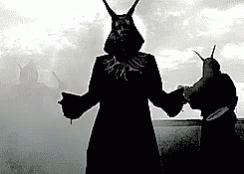 A Black And White Photo Of A Man With Horns Standing Next To Another Man GIF