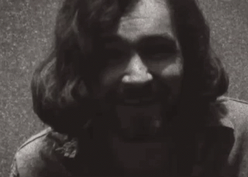 A Black And White Photo Of A Man With Long Hair And A Beard Smiling . GIF
