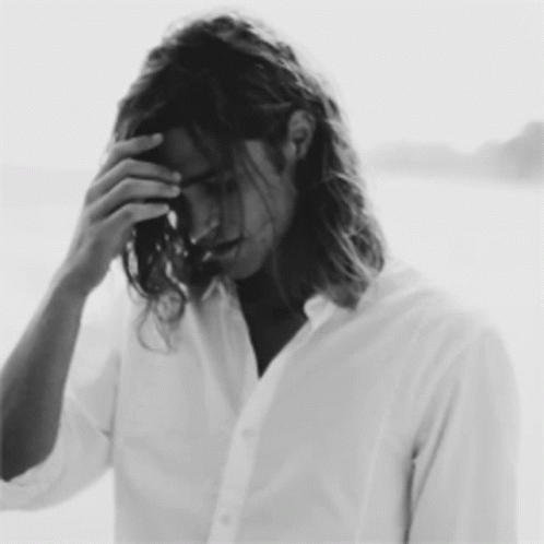 a black and white photo of a man with long hair covering his face