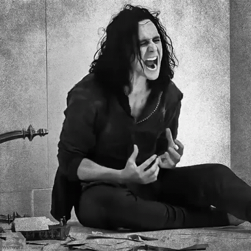 A Black And White Photo Of A Man With Long Hair Sitting On The Floor Screaming GIF