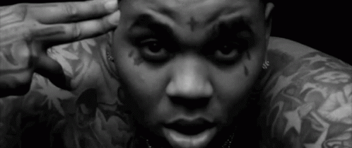 A Black And White Photo Of A Man With Tattoos On His Arms And Face . GIF