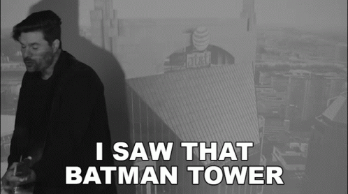 A Black And White Photo Of A Man With The Words I Saw That Batman Tower Below Him GIF